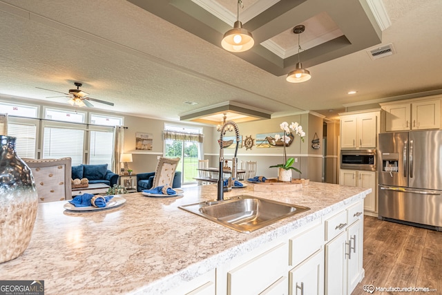 kitchen with appliances with stainless steel finishes, sink, wood-type flooring, ceiling fan, and ornamental molding