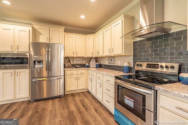 kitchen with appliances with stainless steel finishes, light stone counters, wood-type flooring, wall chimney exhaust hood, and ornamental molding