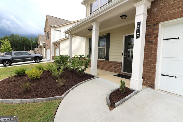 view of exterior entry featuring a porch and a garage