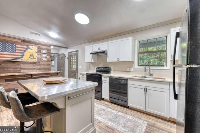 kitchen featuring a breakfast bar, black appliances, white cabinets, sink, and vaulted ceiling