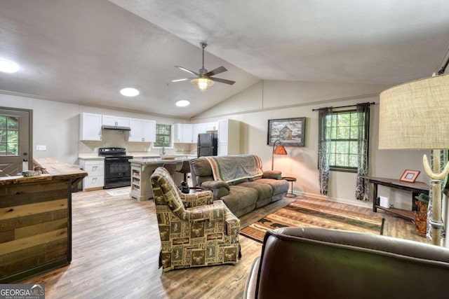 living room with ceiling fan, lofted ceiling, and light wood-type flooring