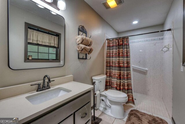 bathroom with tile patterned floors, vanity, toilet, and curtained shower