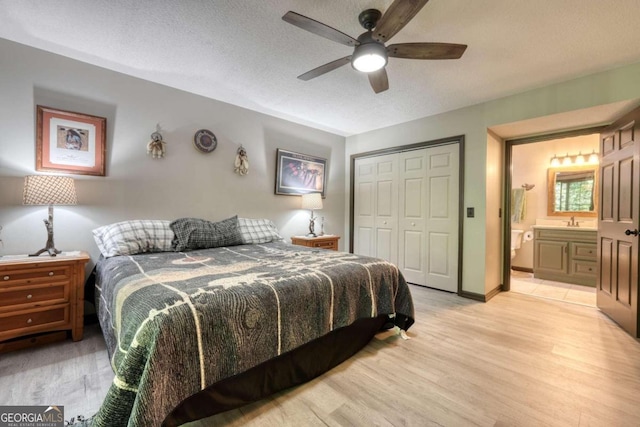 bedroom featuring ensuite bath, ceiling fan, light hardwood / wood-style flooring, a textured ceiling, and a closet