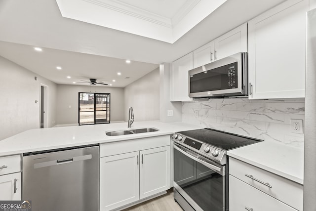 kitchen with appliances with stainless steel finishes, sink, white cabinets, and kitchen peninsula