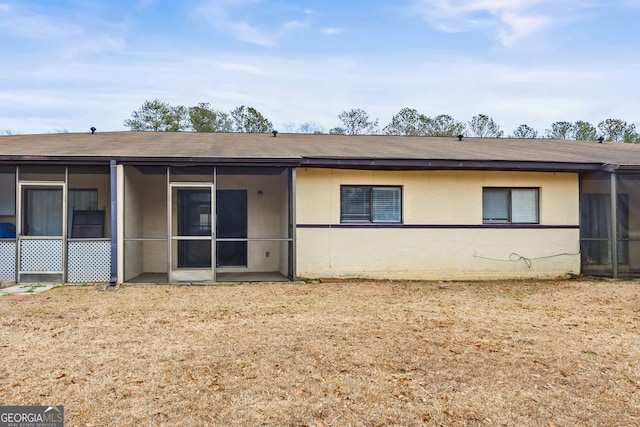 rear view of property with a sunroom and a lawn