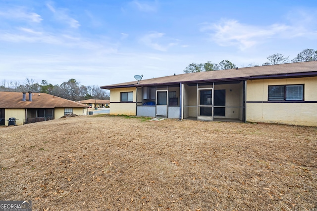 rear view of house with a yard and a sunroom