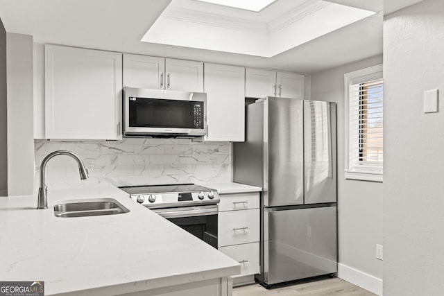 kitchen with sink, white cabinetry, backsplash, stainless steel appliances, and a raised ceiling