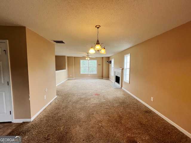 unfurnished dining area with carpet floors, a textured ceiling, and ceiling fan with notable chandelier