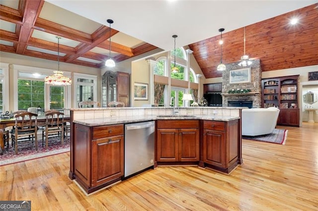 kitchen with sink, a stone fireplace, dishwasher, and light wood-type flooring