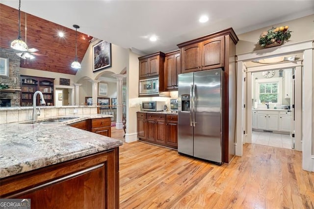 kitchen featuring a fireplace, appliances with stainless steel finishes, light wood-type flooring, and decorative light fixtures