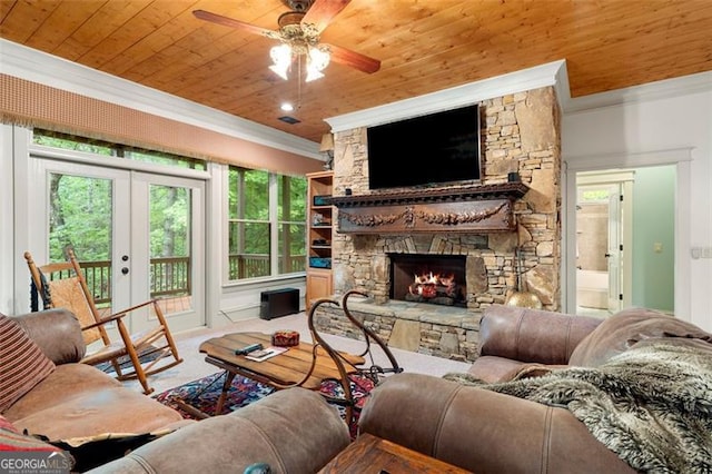 living room featuring ceiling fan, a stone fireplace, crown molding, and wood ceiling