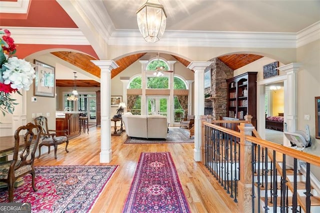 interior space featuring light hardwood / wood-style flooring, an inviting chandelier, decorative columns, and a fireplace