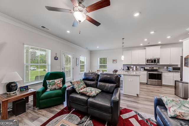 living room with light wood-type flooring, ceiling fan, and crown molding