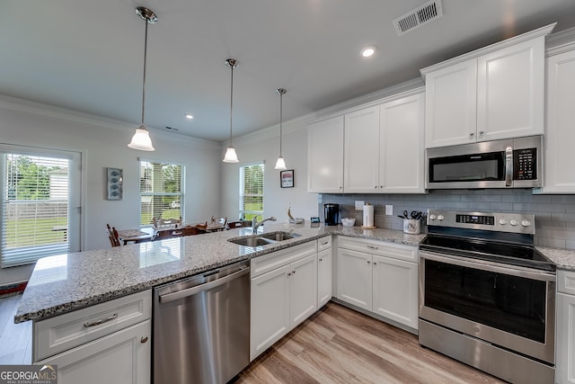 kitchen featuring kitchen peninsula, appliances with stainless steel finishes, decorative light fixtures, white cabinets, and sink