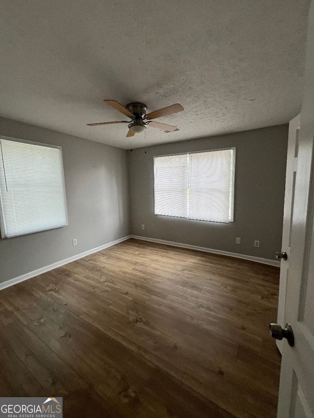 empty room with a textured ceiling, wood-type flooring, and ceiling fan