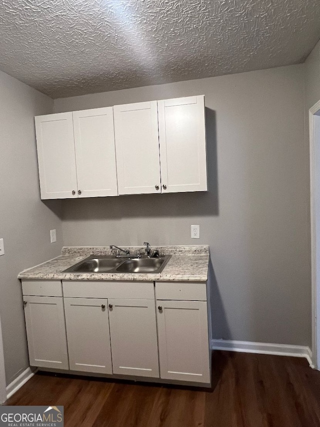 kitchen featuring sink, dark hardwood / wood-style floors, white cabinets, and a textured ceiling