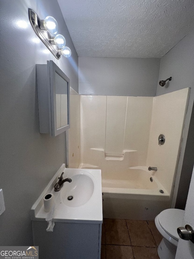 full bathroom featuring a textured ceiling, washtub / shower combination, toilet, vanity, and tile patterned floors