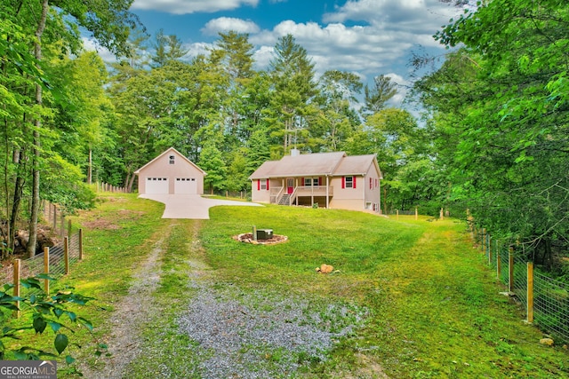 view of yard featuring a garage, driveway, an outdoor structure, and fence