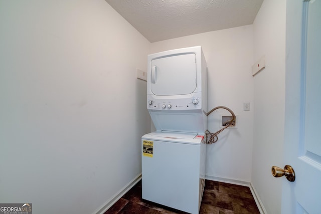 laundry area featuring laundry area, stacked washer / dryer, baseboards, and a textured ceiling