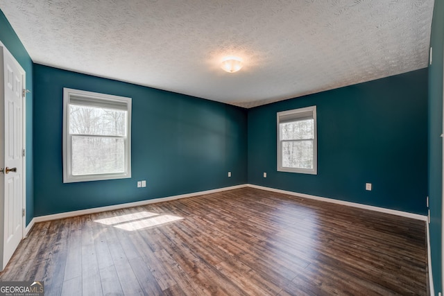 spare room featuring plenty of natural light, wood finished floors, and baseboards