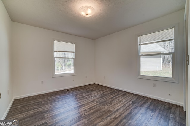 empty room featuring baseboards, a textured ceiling, and dark wood-style flooring