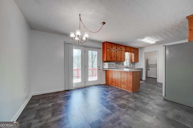 kitchen with white microwave, a chandelier, light countertops, a peninsula, and a sink