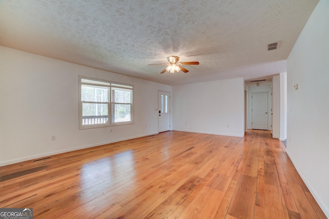 empty room featuring a textured ceiling, light wood-style flooring, visible vents, and ceiling fan