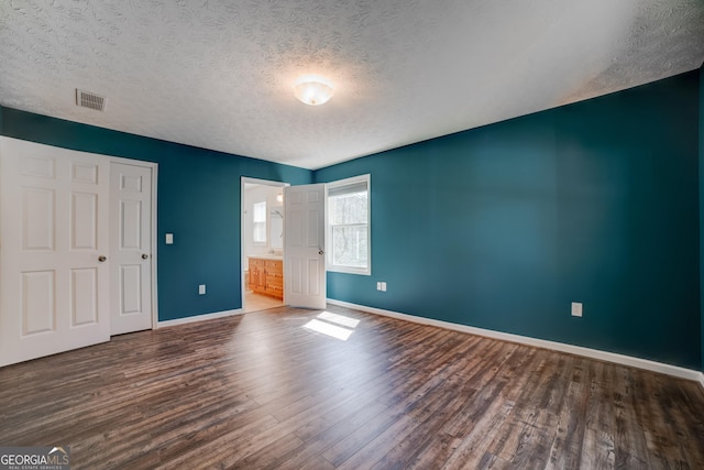 unfurnished bedroom featuring visible vents, wood finished floors, baseboards, and a textured ceiling