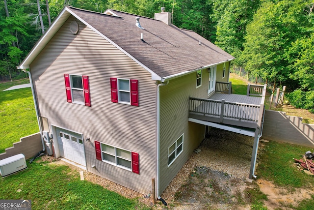 view of side of home featuring a lawn, roof with shingles, an attached garage, a wooden deck, and a chimney