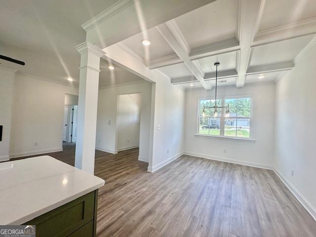 interior space with ornate columns, beamed ceiling, coffered ceiling, light hardwood / wood-style floors, and crown molding