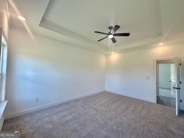 carpeted empty room featuring crown molding, ceiling fan, and a tray ceiling