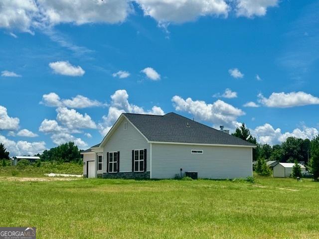 view of side of property featuring cooling unit and a lawn