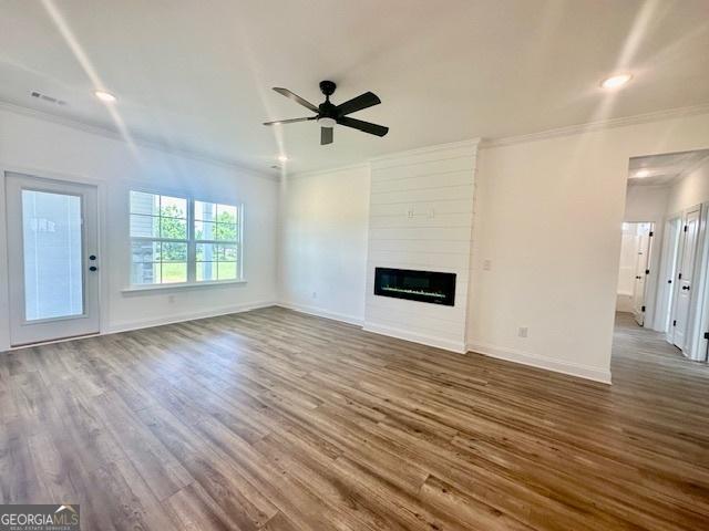 unfurnished living room with crown molding, dark hardwood / wood-style floors, a fireplace, and ceiling fan