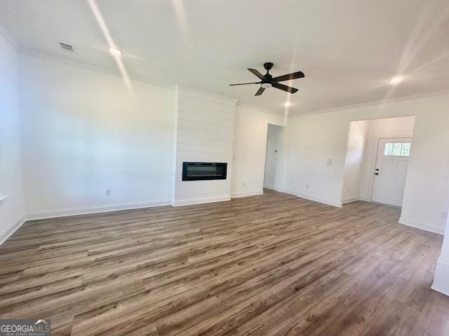 unfurnished living room with heating unit, hardwood / wood-style floors, a fireplace, ornamental molding, and ceiling fan