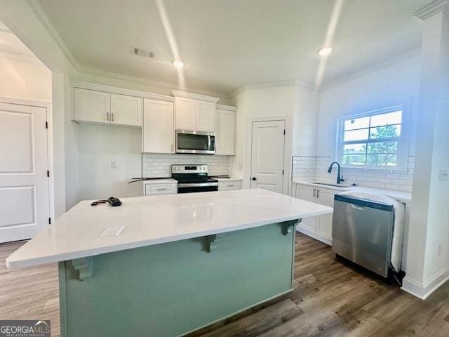 kitchen featuring a kitchen island, appliances with stainless steel finishes, a breakfast bar, and white cabinets