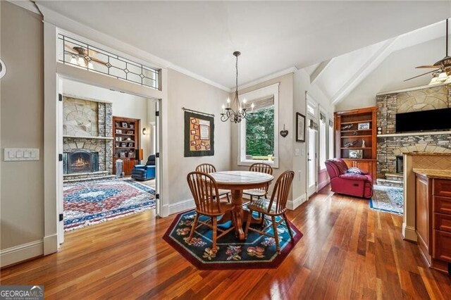 kitchen with a stone fireplace, dark wood-type flooring, stainless steel fridge, and vaulted ceiling