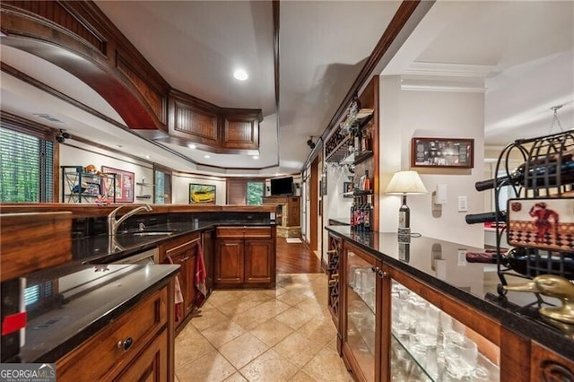 kitchen with a fireplace, light wood-type flooring, ornamental molding, a raised ceiling, and kitchen peninsula