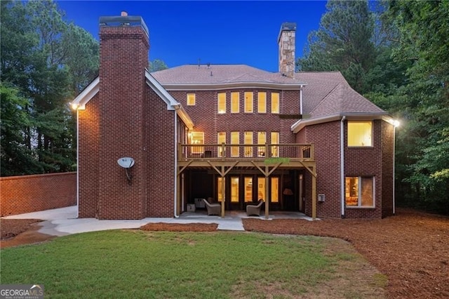 back house at night featuring a patio area and a yard