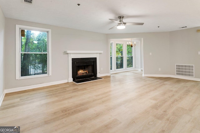 unfurnished living room with a fireplace with flush hearth, light wood-type flooring, visible vents, and baseboards