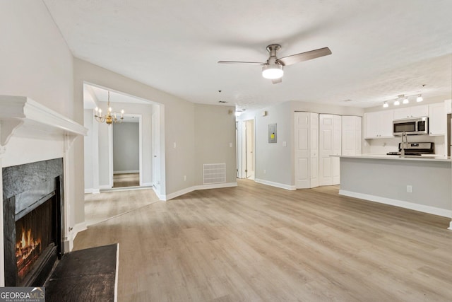 unfurnished living room featuring light wood-style floors, baseboards, visible vents, and a high end fireplace