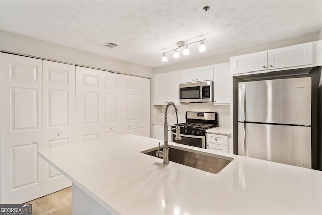 kitchen featuring appliances with stainless steel finishes, light countertops, white cabinets, and a sink