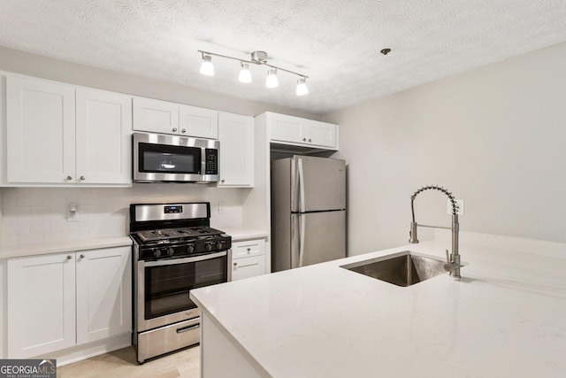 kitchen featuring decorative backsplash, appliances with stainless steel finishes, light countertops, white cabinetry, and a sink