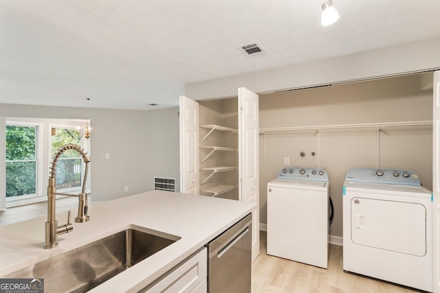 laundry room featuring visible vents, light wood-style floors, a sink, washer and dryer, and laundry area