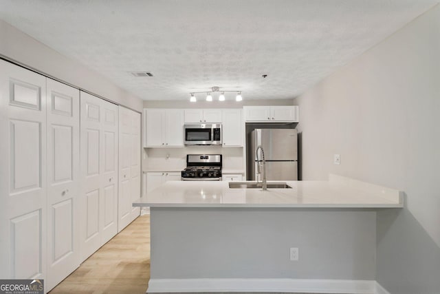 kitchen with visible vents, white cabinets, appliances with stainless steel finishes, light countertops, and light wood-type flooring