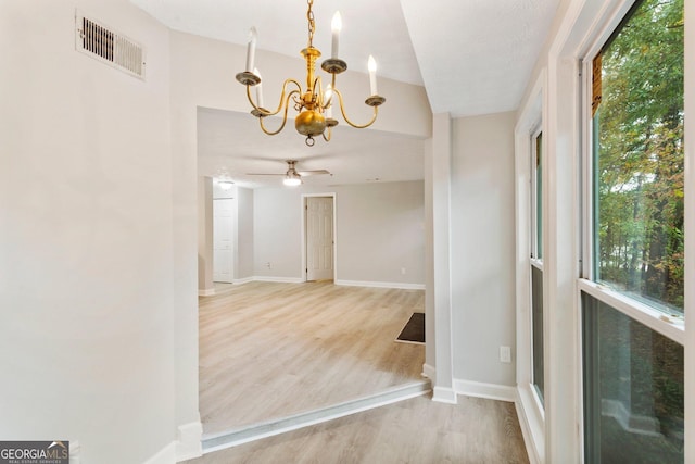 unfurnished room featuring visible vents, light wood-style flooring, baseboards, and ceiling fan with notable chandelier