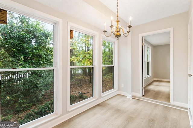 unfurnished dining area featuring light wood-style flooring, baseboards, and a chandelier