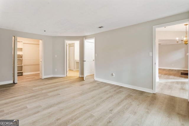 unfurnished bedroom featuring light wood-style flooring, a closet, and a spacious closet