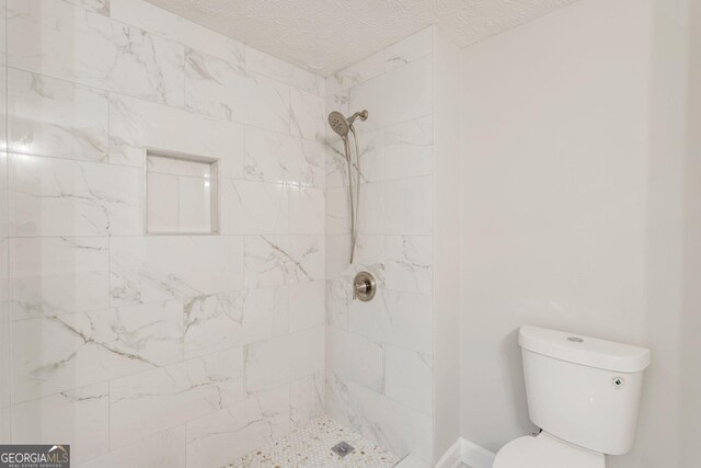 bathroom featuring a tile shower, a textured ceiling, and toilet