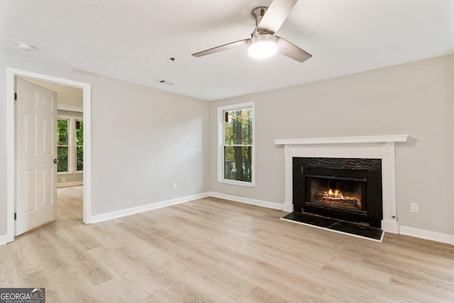 unfurnished living room featuring light wood finished floors, a premium fireplace, and a wealth of natural light