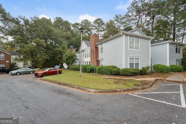 view of side of property featuring uncovered parking and a yard